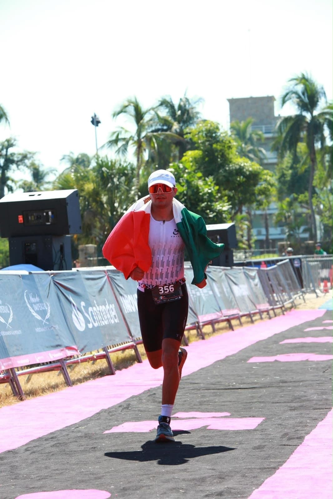 Lalo cruzando la meta de un triatlón con la bandera de México en los hombros