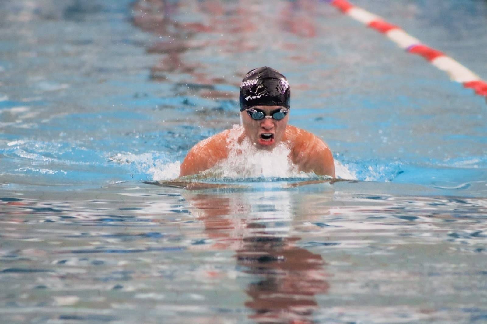 Lalo nadando pecho en competencia, con goggles y gorra negra